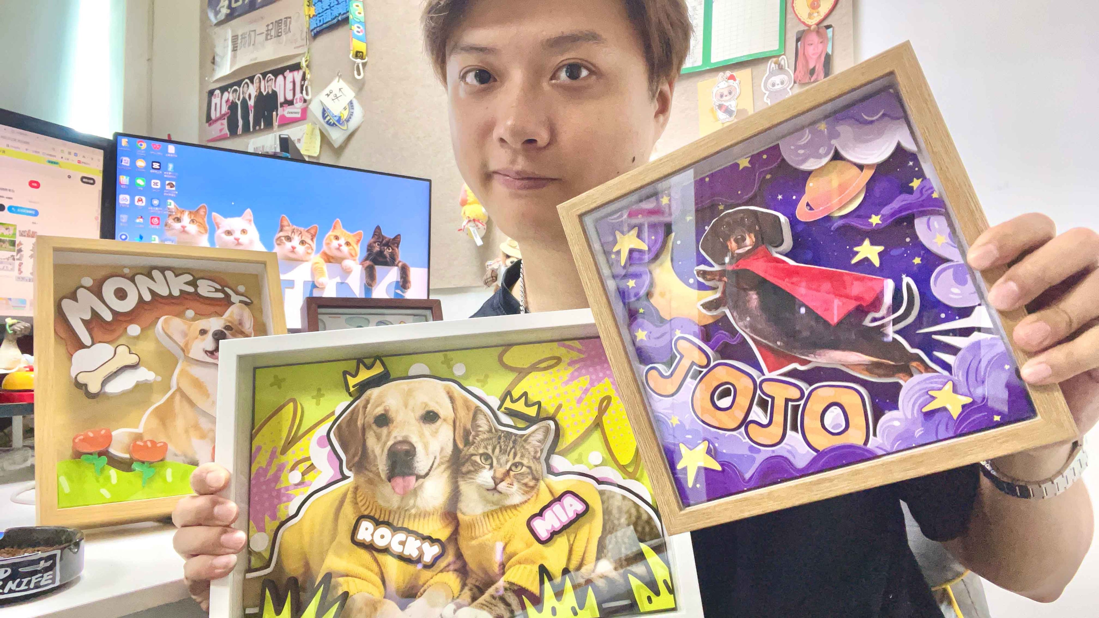 MooWeeStudio's maker holding three handcrafted 3D pet portrait shadow boxes of a corgi, a Labrador with a tabby cat, and a dachshund in wooden and white frames, shown as the hero image on the FAQ page
