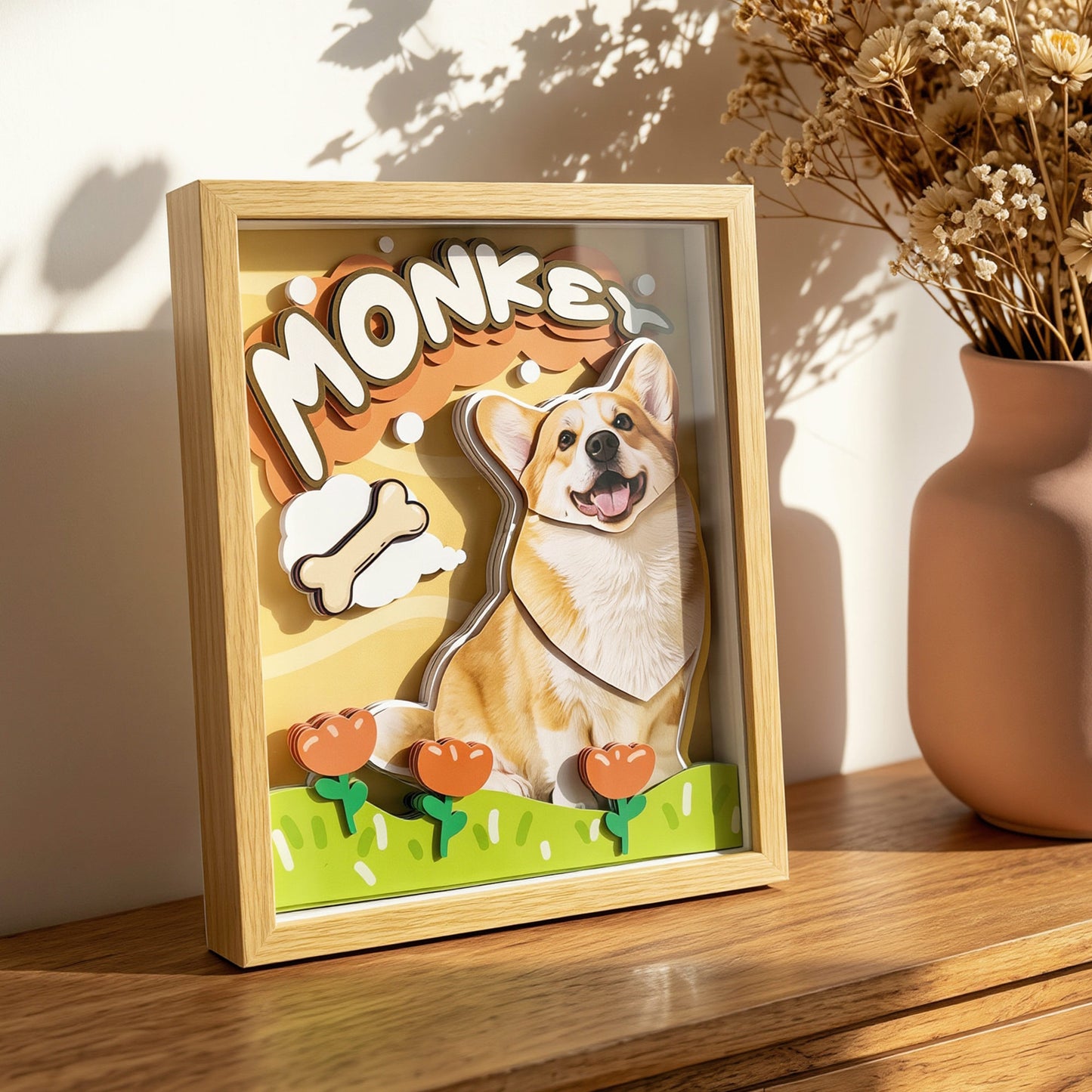 Customized 3D framed corgi dog shadow box displayed next to a vase with dried flowers on a wooden surface.